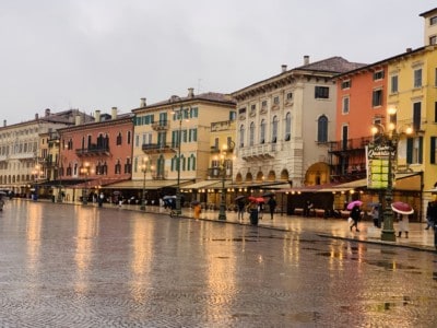 The Piazza Bra with its coloured building lining the street.  The streets is wet from rain and the light is dim
