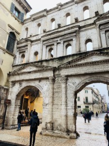 A picture of La Porta Borsari, a city gate.  This has arches to walk through into the street.  It is white