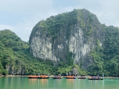 A view of another part of Halong Bay that you may see on a Halong Bay day cruise.  There's a massive limestone rock in the background and lots of bamboo boats sailing on the water