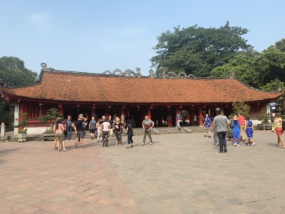 Part of the inside of the Temple of Literature.  There is a wide open square here with a temple at the back.  You can see tourists walking in the square.