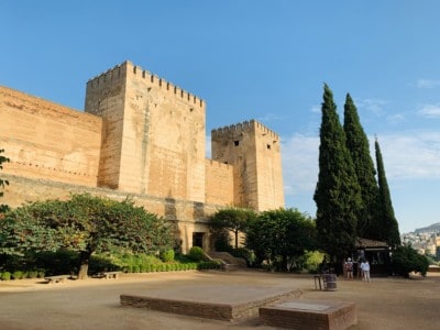 Picture of the outside of the Alcazaba with trees and an open area in front