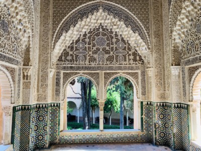 A side alcove in the Nasrid Palace that you can see when visiting the Alhambra.  This has an arch and windows looking out onto a leafy outside area and beautiful ornate Moorish design