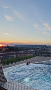 Image of the rooftop pool in the spa - you can see two people in the pool and there are views out across Zurich