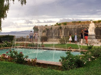 The Durrell Park. There's a long rectangular pool with small fountain streams flowing over it. There is a state in the background.