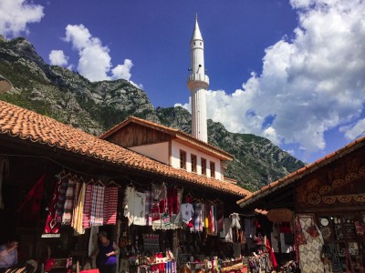 The bazaar in Kruja with the mosque's white minaret in the background and some mountains. 