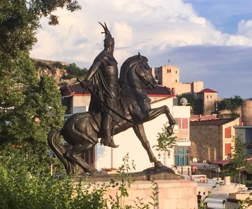 The Skanderbeg statue - it sits on a pedestal with buildings in the background.