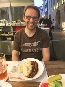 My partner eating at an outside table at the Zeughauskeller restaurant.  He had 2 large sausages with potato salad in a gravy.  He has a beer on the side and a small plate of pickles.