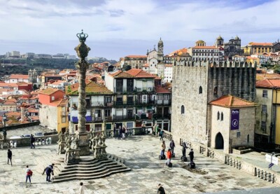 Looking out from the cathedral across a square with a tall monument in it and across the houses and buildings of Porto.